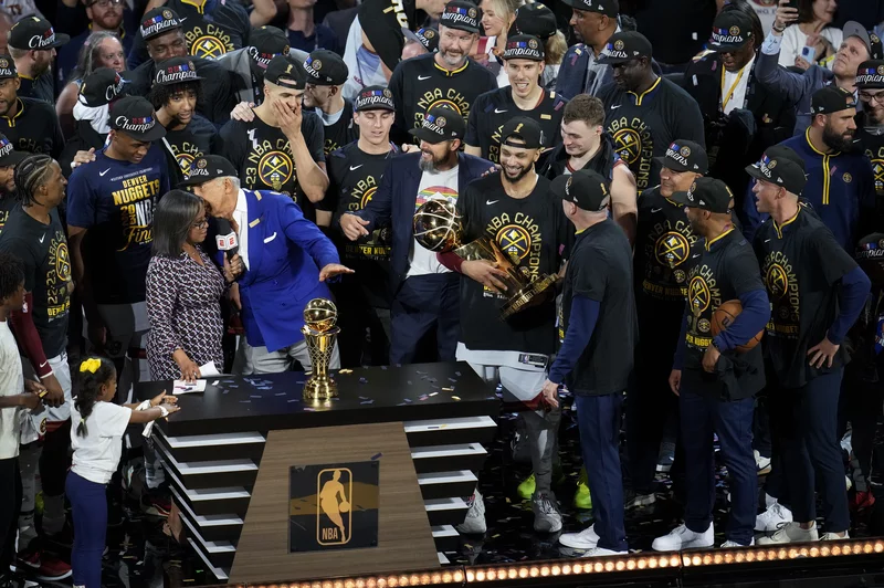 Denver Nuggets players, coaches and owners hold up the Larry O'Brien NBA Championship Trophy after the team's victory over the Miami Heat in Game 5 of basketball's NBA Finals, Monday, June 12, 2023, in Denver.